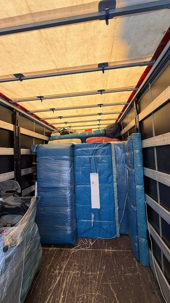 Kamyon içinde battaniye ve streçle paketlenmiş, düzenli istiflenmiş eşyalar